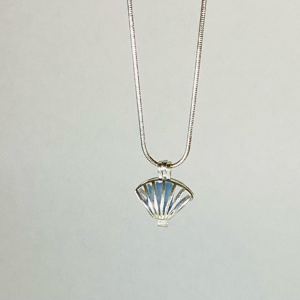 Blue sea glass necklace in silver seashell locket.